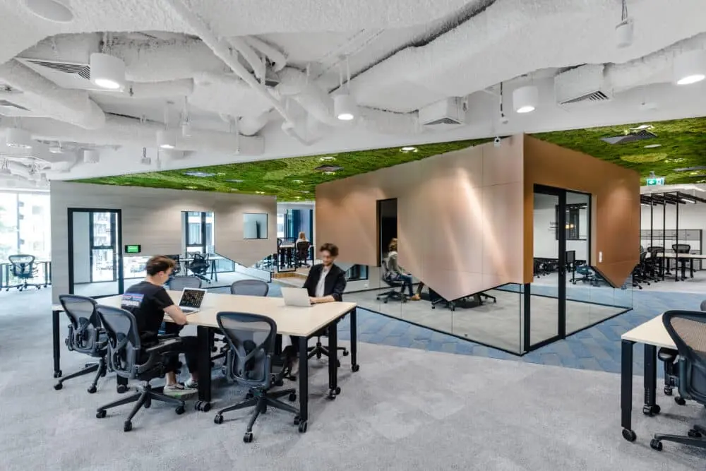 Modern coworking space with professionals working and an occupancy dashboard on screen.